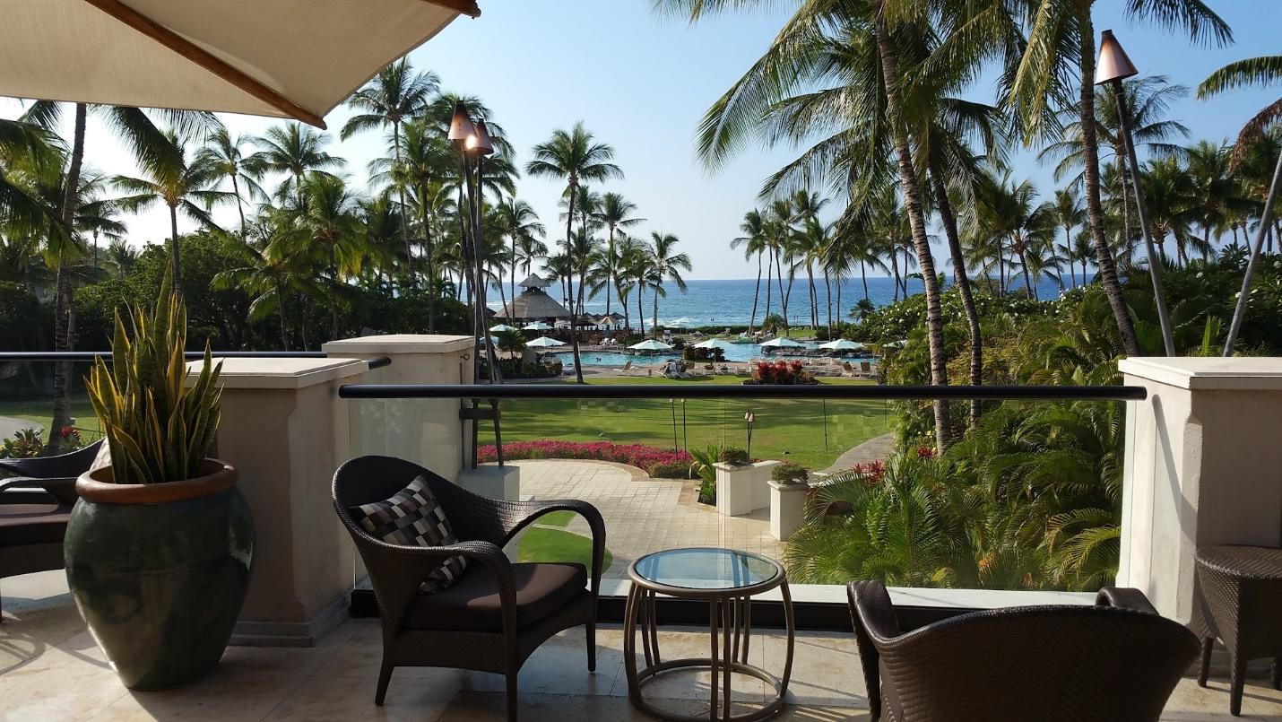 A chair and table on a balcony overlooking a beach

Description automatically generated